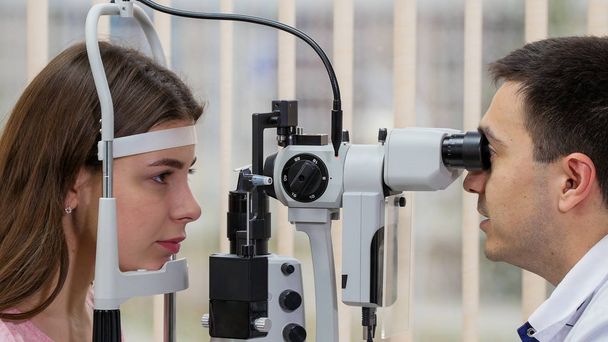 oogheelkundige behandeling - jonge vrouw controleren van haar gezichtsscherpte met een speciale apparatuur in de heldere kast - Foto, afbeelding