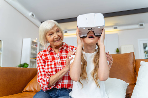 Smiling grandparent embracing her grandchild in VR goggles - Фото, изображение
