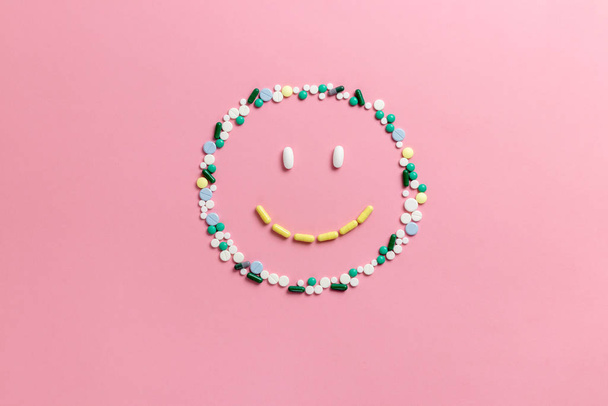 Composition of pills and capsules on a pink background in the form of a smile. Happy emotions. Psychological help. Copy space. View from above. Flat lay. - Фото, изображение