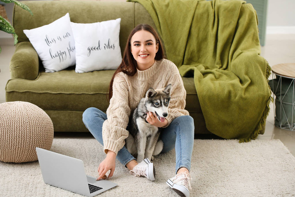 Young woman with funny husky puppy and laptop resting at home - Foto, Bild