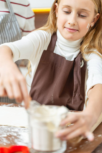 Girl scooping the flour from a glass - Photo, image