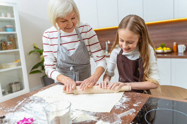 Senior woman and her granddaughter making the dough - Фото, изображение
