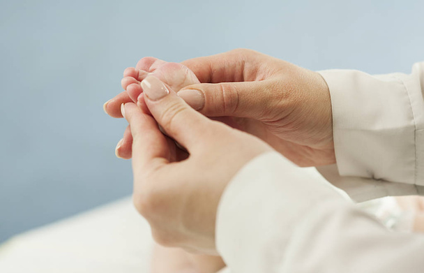 Madre amor Madre sosteniendo los pies de su pequeño bebé, de cerca. Examen de la piel del concepto por un médico
 - Foto, Imagen