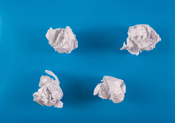 Crumpled ball sheet of paper on a blue background - 写真・画像