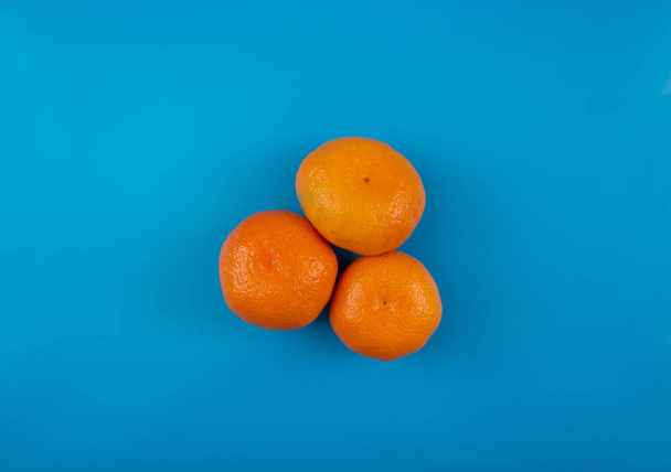 Bright juicy tangerine on a blue background - Foto, Imagem