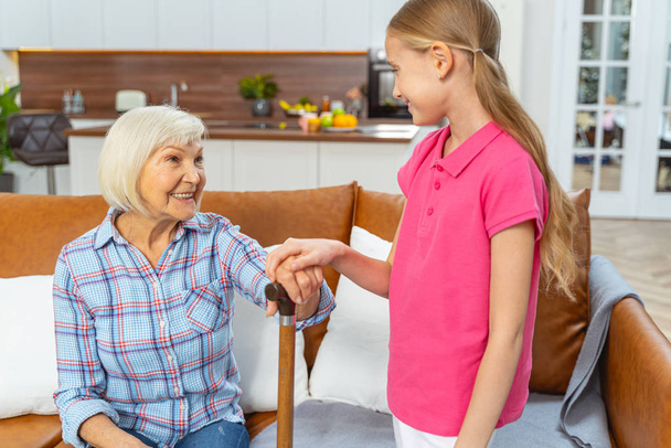 Caring young girl touching her grandmother hand - Foto, Imagen
