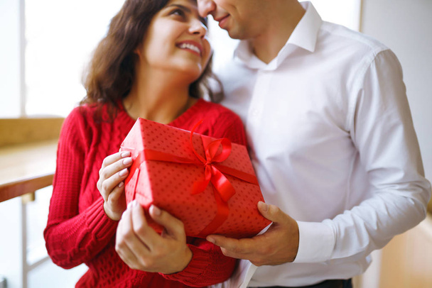 Close up of happy couple with christmas gift hugging. Cheerful couple with gift in hands enjoying together on Christmas eve. Lovers give each other gifts. Valentine's Day concept. - Valokuva, kuva