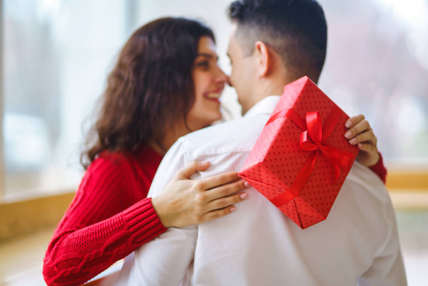 Close up of happy couple with christmas gift hugging. Cheerful couple with gift in hands enjoying together on Christmas eve. Lovers give each other gifts. Valentine's Day concept. - Fotó, kép
