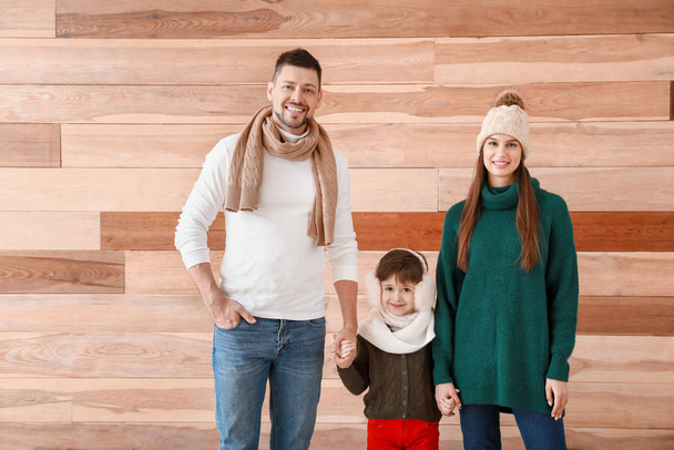 Happy family in winter clothes on wooden background - 写真・画像