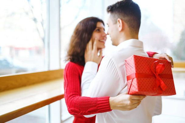 Close up of happy couple with christmas gift hugging. Cheerful couple with gift in hands enjoying together on Christmas eve. Lovers give each other gifts. Valentine's Day concept. - Fotografie, Obrázek