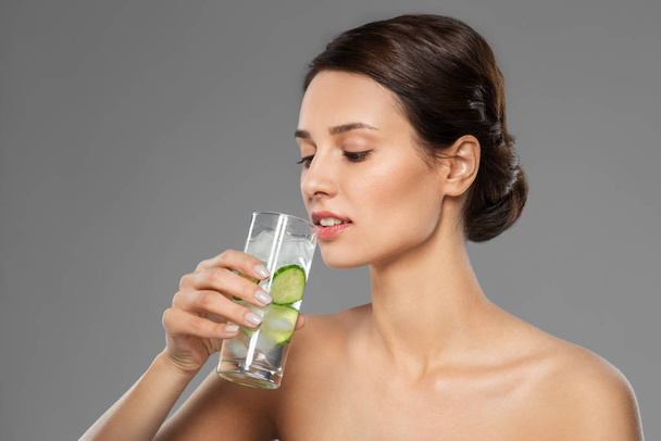 woman drinking water with cucumber and ice - Foto, Imagen