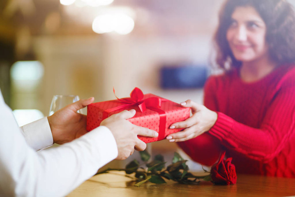 Man giving a christmas present to his girlfriend. Cheerful couple with gift in hands enjoying together on Christmas eve. Winter holidays concept. Lovers give each other gifts. Valentine's Day concept. - Fotografie, Obrázek
