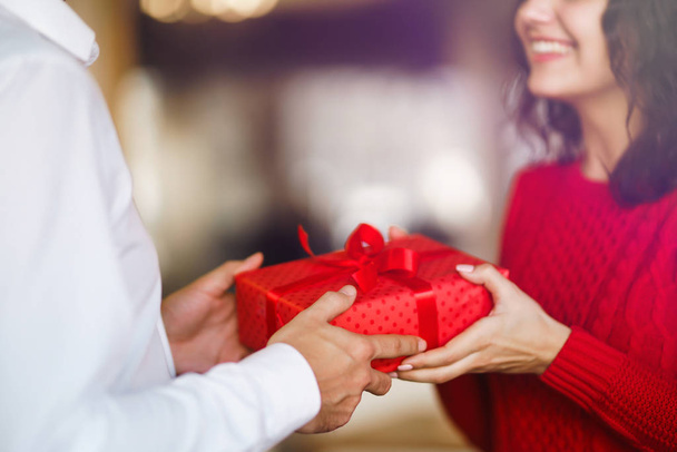 Man giving a christmas present to his girlfriend. Cheerful couple with gift in hands enjoying together on Christmas eve. Winter holidays concept. Lovers give each other gifts. Valentine's Day concept. - Фото, изображение