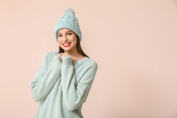 Happy young woman in winter clothes on light background - Фото, изображение