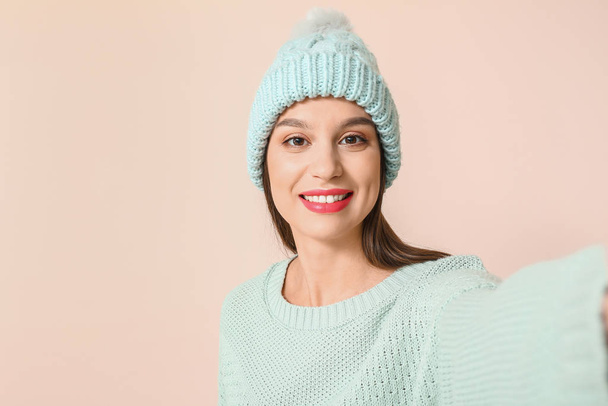 Joyeux jeune femme en vêtements d'hiver prenant selfie sur fond clair
 - Photo, image