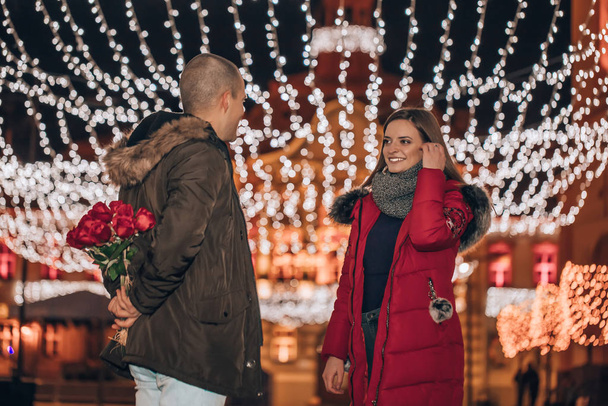 Man hiding a bouquet of roses from his girlfriend at night - Valokuva, kuva