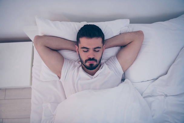 Close-up top above high angle view portrait of his he nice attractive brunette guy lying on white bed resting sleeping peacefully at night late evening home hotel room flat indoors - Photo, Image