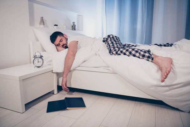 Πορτρέτο του ο ωραίος ελκυστική ηρεμία κουρασμένος τύπος που βρίσκεται στο κρεβάτι αποκοιμήθηκε μετά από δύσκολη μέρα εργασίας το βράδυ αργά το βράδυ σπίτι ξενοδοχείο φωτίζεται δωμάτιο επίπεδη σπίτι - Φωτογραφία, εικόνα