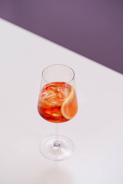 vaso de aperol spritz cóctel con hielo y naranja sobre mesa blanca
  - Foto, Imagen