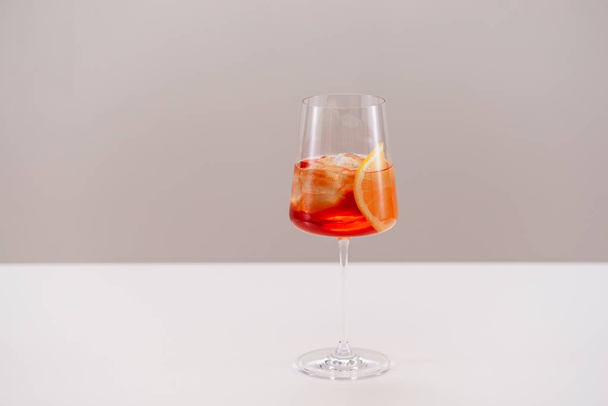 glass of aperol spritz cocktail with ice and orange on light background - Fotó, kép