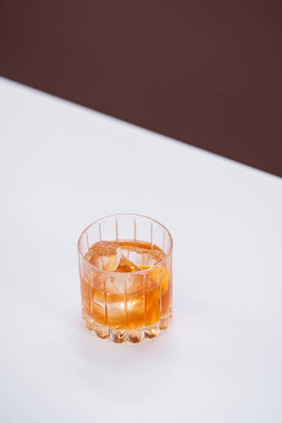 glass and whiskey and ice cubes on white table - Zdjęcie, obraz