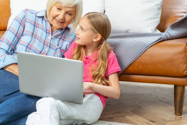 Girl with a laptop looking at her grandmother - Foto, Imagen