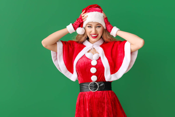 Krásná mladá žena oblečená jako Santa na barevném pozadí - Fotografie, Obrázek