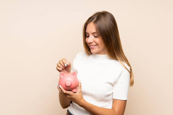 Young blonde woman over isolated background holding a big piggybank - Φωτογραφία, εικόνα