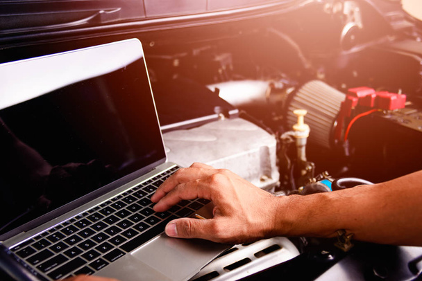 Professional car repair or maintenance mechanic engine working service with laptop computer at workshop - 写真・画像