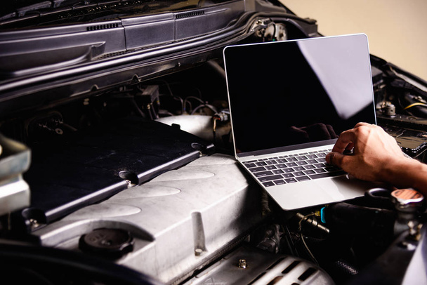 Serviço de trabalho mecânico do motor da reparação ou da manutenção profissional do carro com computador portátil na oficina
 - Foto, Imagem