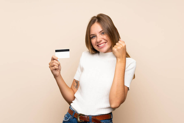 Młoda blondynka na odosobnionym tle z kartą kredytową - Zdjęcie, obraz