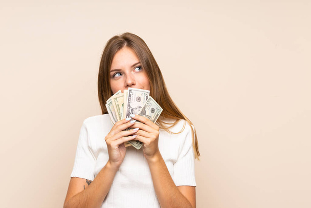 Fiatal szőke nő elszigetelt háttér figyelembe egy csomó pénzt - Fotó, kép