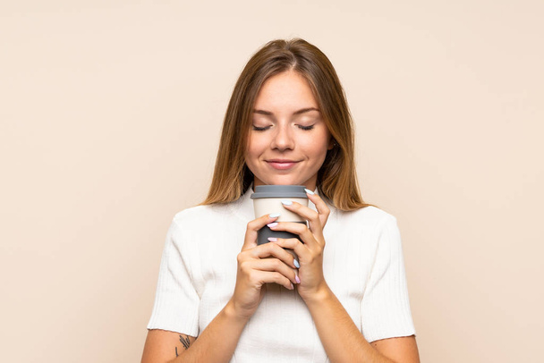 Mladé blondýny žena přes izolované pozadí drží kávu odnést - Fotografie, Obrázek