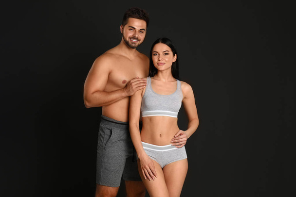 Young couple in grey sportive underwear on black background - Foto, afbeelding