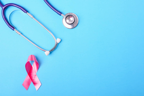 Breast cancer month concept, flat lay top view, pink ribbon and stethoscope on blue background with copy space for your text - Φωτογραφία, εικόνα