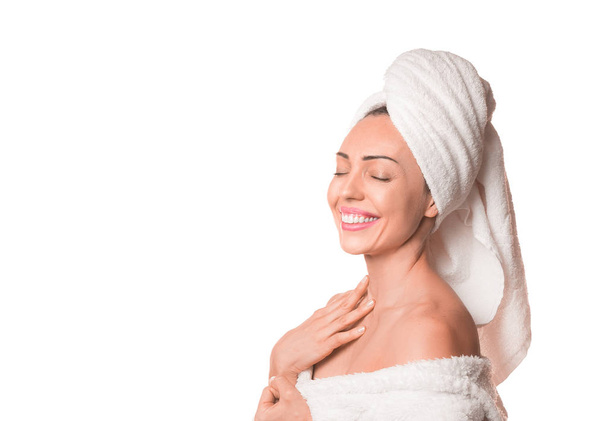 スパスキンケア美容女性はシャワー後頭の上にタオルで髪を乾燥させます。白い背景に隔離された目を閉じて柔らかい肌に触れる美しい笑顔の女性. - 写真・画像