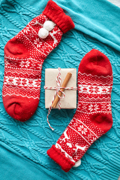 Χριστουγεννιάτικη σύνθεση, κόκκινες κάλτσες με δώρο σε μπλε πλεκτό πουλόβερ - Φωτογραφία, εικόνα