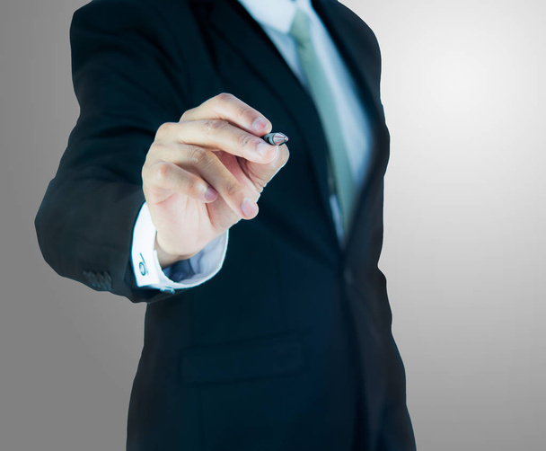 Liikemies seisoo ryhti käsi pidä kynä eristetty yli harmaa tausta
 - Valokuva, kuva