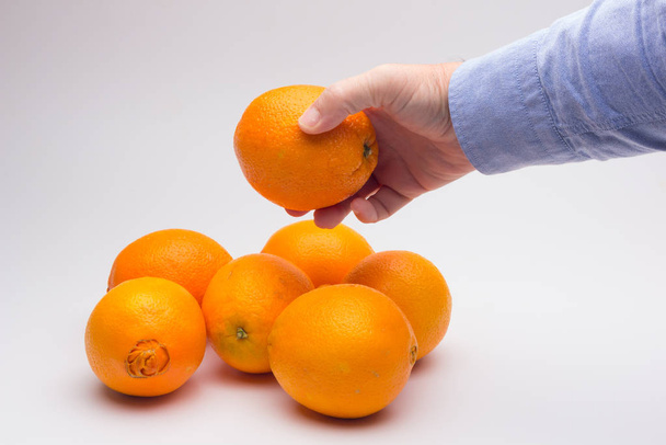 Appelsiinihedelmät aikuisen kädessä
 - Valokuva, kuva