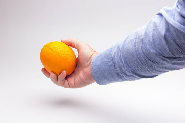 Naranja en la mano de una persona adulta, preparando un jugo
 - Foto, Imagen
