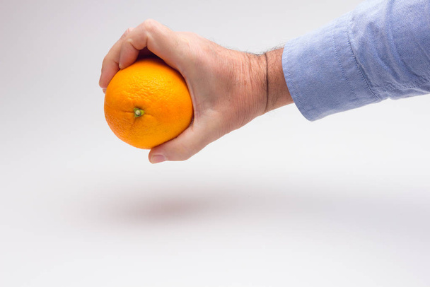 Orange dans la main d'un adulte, la préparation d'un jus
 - Photo, image