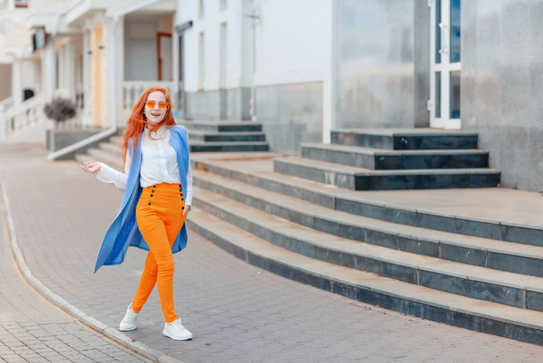 Cheerful redhead young woman in bright clothes on the street - Photo, Image