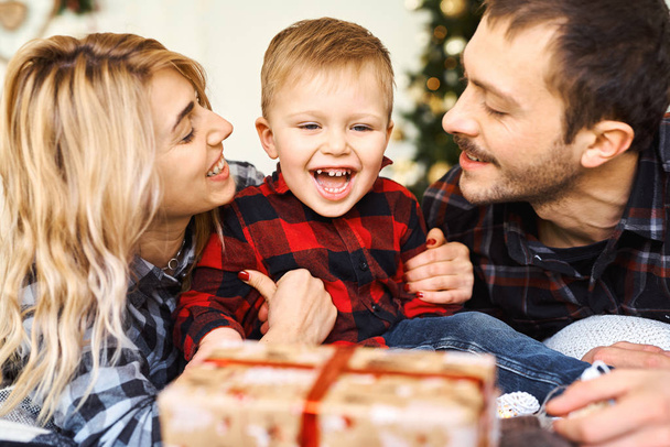 Young parents giving a Christmas present to little son at Chrismas morning in bed. - Foto, Bild