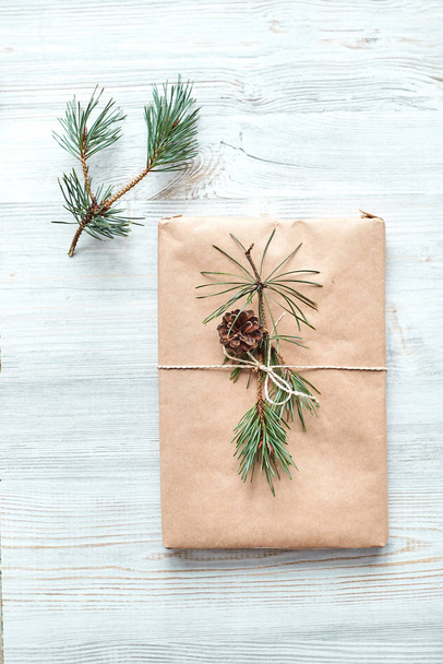 gift wrapping for a book or laptop in craft paper tied with twine rope and decorated with a fir branch with a cone  - Φωτογραφία, εικόνα