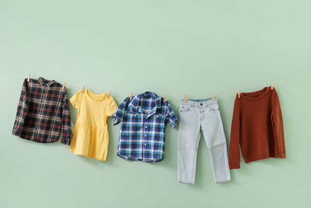 Clean clothes hanging on rope against color background - Photo, Image