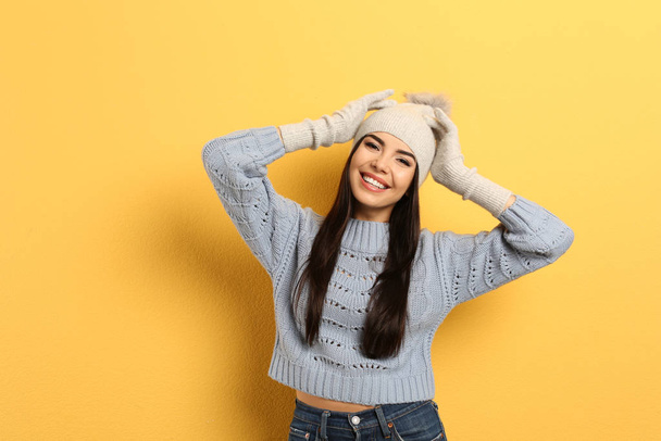 Happy young woman in warm clothes on yellow background. Winter vacation - Фото, зображення