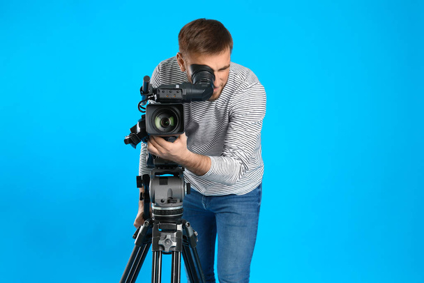 Operator with professional video camera on blue background - Fotoğraf, Görsel