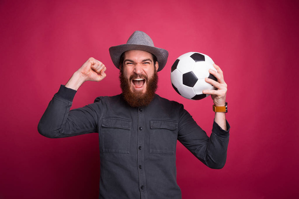Photo of amazed man holding soccer ball and celebrating success - Фото, изображение