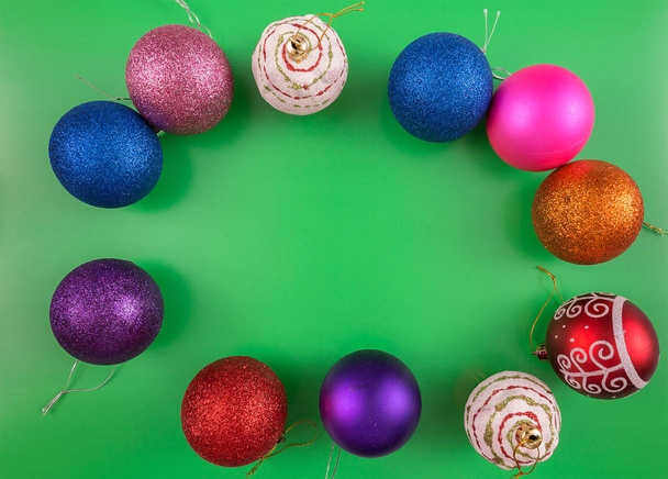 Christmas background with Christmas tree colored toys, balls sprinkled with sequins on a flat surface with a place for the inscription copy space, top view, green substrate - Foto, imagen