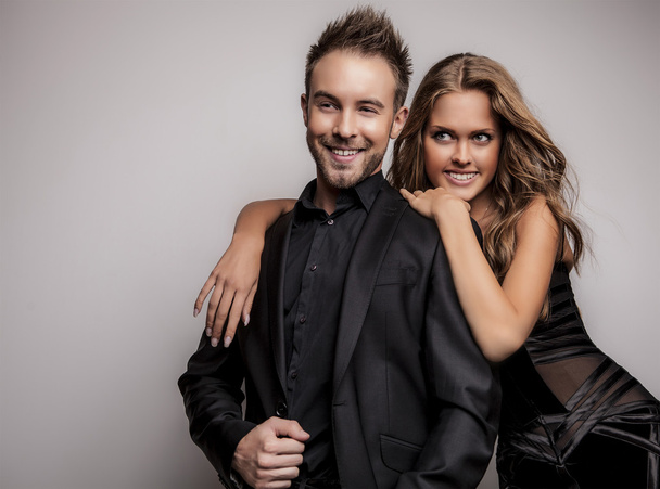 Portrait of young attractive couple posing at studio dressed in black fashionable clothes. - Фото, изображение